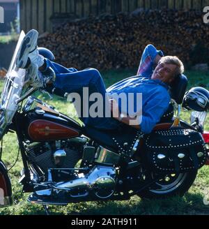 Der deutsche Schauspielleiter Siegfried Rauch porträtiert mit einem Motorrad, Deutschland 1980. Der deutsche Schauspieler Siegfried Rauch wird mit seinem Motorrad, deutschland 1980, dargestellt. Stockfoto