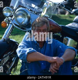 Der deutsche Schauspielleiter Siegfried Rauch porträtiert mit einem Motorrad, Deutschland 1980. Der deutsche Schauspieler Siegfried Rauch wird mit seinem Motorrad, deutschland 1980, dargestellt. Stockfoto