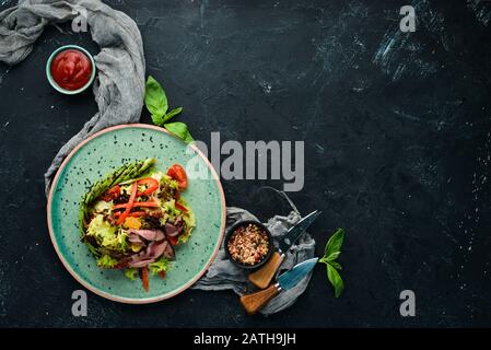 Gemüsesalat mit Avocado und Kalbfleisch. In der Platte. Draufsicht. Freier Speicherplatz für Ihren Text. Rustikaler Stil. Stockfoto