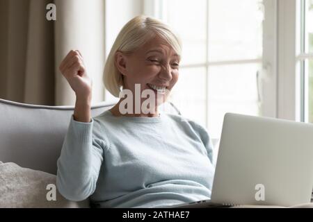 Überfreute Seniorinnen triumphieren beim Lesen guter Nachrichten auf dem Laptop Stockfoto