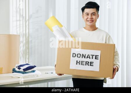 Portrait des freudig aufgeregten jungen Asiaten mit Spenderbox Stockfoto