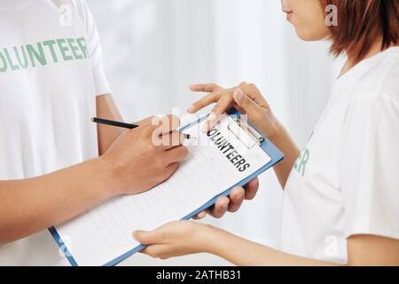 Freiwillige, die eine Liste der Personen aufschreiben, die an einer Wohltätigkeitsveranstaltung teilnehmen Stockfoto