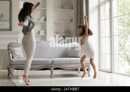 Energische junge Mutter tanzt mit glücklicher kleiner Tochter Stockfoto