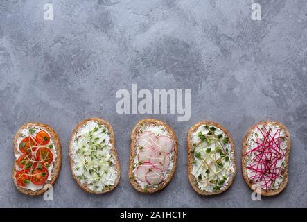 Ein flacher Lay mit vegetarischen Sandwiches mit Curd Cheese, Gemüse und Mikrogrüns auf grauem Hintergrund. Es gibt Platz für Text Stockfoto