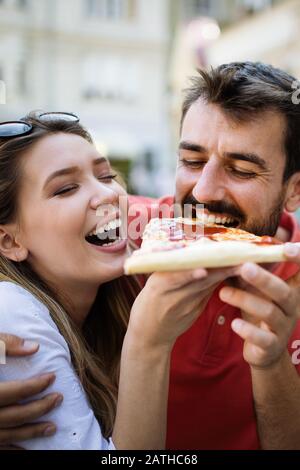 Glückliches Paar lachen und essen Pizza, Spaß zusammen haben Stockfoto