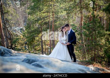 Schöne Jungvermählten umarmen vor der Kulisse von Felsen und Berge. Stilvolle braut und schöne Braut stehen auf der Klippe. Hochzeit portrait Stockfoto