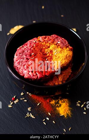Lebensmittelzubereitungszutaten Konzept Bio roh Hackfleisch oder gemahlenes Rindfleisch mit Gewürzen für orientalische Lebensmittel Keema Curry auf schwarzem Schieferstein mit c Stockfoto