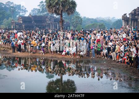 Krong Siem Reap, Kambodscha - 6. April 2013: Touristenmassen entlang des Sees mit Reflexion von Ankor Wat warten auf Sonnenaufgang Stockfoto