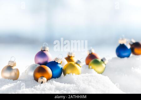 Bunte Bällchen oder weihnachtskugeln im Schnee liegen, winterlicher Landschaftshintergrund mit Kopierraum Stockfoto