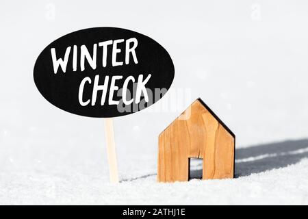 Kleines Holzhaus und Anmeldung im Schnee, Text Winterscheck, Konzeptkontrolle und Service für das eigene Zuhause Stockfoto
