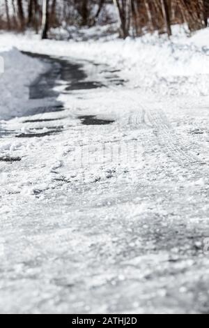 Schwarzeis und Schnee auf der Landstraße oder Straße, Gefahr und Unfallgefahr in der Wintersaison, Copyspace Stockfoto