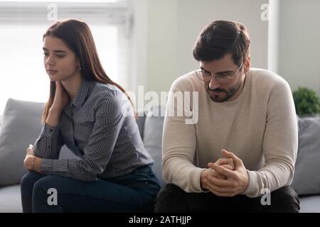 Paare, die auf der Couch sitzen, denken, fühlen sich über Beziehungsprobleme beunruhigt Stockfoto