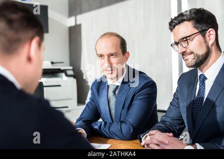 Team von selbstbewussten, erfolgreichen Geschäftsleuten, die die Vertragsbedingungen bei der Geschäftsbesprechung in modernen Unternehmensbüros besprechen. Stockfoto