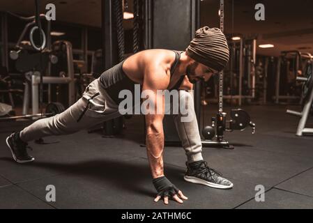 Ein bärtiger sportlicher Mann im Fitnessstudio macht Yoga. Krieger-Pose. Virabhadrasana Position Stockfoto