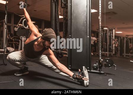 Ein bärtiger sportlicher Mann im Fitnessstudio macht Yoga- und Kampfkunstübungen. Stockfoto