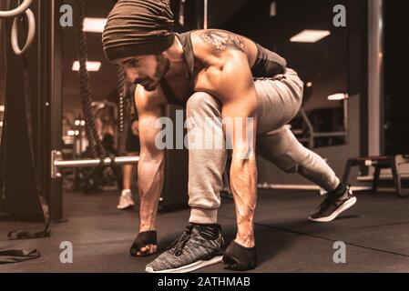 Ein bärtiger sportlicher Mann im Fitnessstudio macht Yoga- und Kampfkunstübungen. Stockfoto