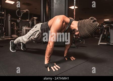 Ein bärtiger sportlicher Mann in der Turnhalle macht Yoga-Übungen, übt das stehen in der Plankpose, macht Push-up- oder Push-Up-Übungen. Stockfoto