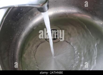 Fließendes Wasser aus einem Wasserhahn in einem metallischen Küchenwaschbecken Stockfoto