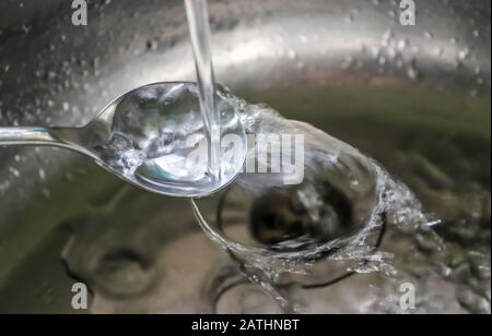 Fließendes Wasser aus einem Wasserhahn in einem metallischen Küchenwaschbecken Stockfoto