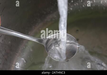Fließendes Wasser aus einem Wasserhahn in einem metallischen Küchenwaschbecken Stockfoto