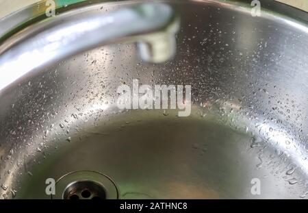 Fließendes Wasser aus einem Wasserhahn in einem metallischen Küchenwaschbecken Stockfoto