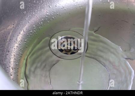 Fließendes Wasser aus einem Wasserhahn in einem metallischen Küchenwaschbecken Stockfoto