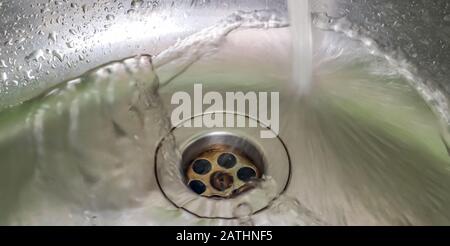 Fließendes Wasser aus einem Wasserhahn in einem metallischen Küchenwaschbecken Stockfoto