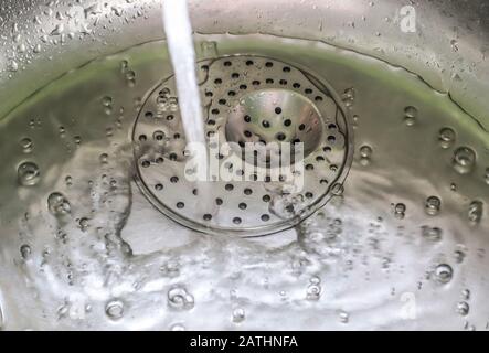 Fließendes Wasser aus einem Wasserhahn in einem metallischen Küchenwaschbecken Stockfoto