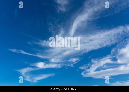 Wispige weiße Wolkenbildung gegen einen leuchtend blauen Himmel. Perry Green, Much Hadham, Hertfordshire. GROSSBRITANNIEN Stockfoto