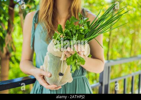 Frische Grüns in einer wiederverwendbaren Tasche in den Händen einer jungen Frau. Null-Abfall-Konzept Stockfoto