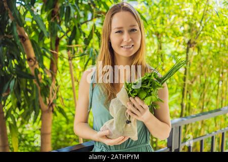 Frische Grüns in einer wiederverwendbaren Tasche in den Händen einer jungen Frau. Null-Abfall-Konzept Stockfoto