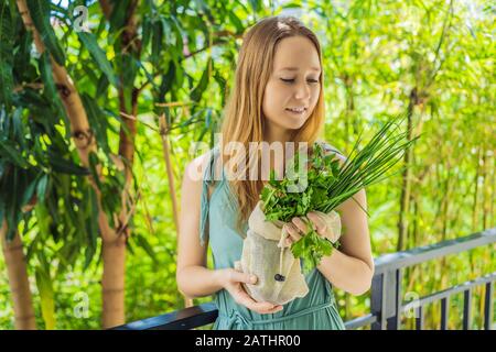 Frische Grüns in einer wiederverwendbaren Tasche in den Händen einer jungen Frau. Null-Abfall-Konzept Stockfoto