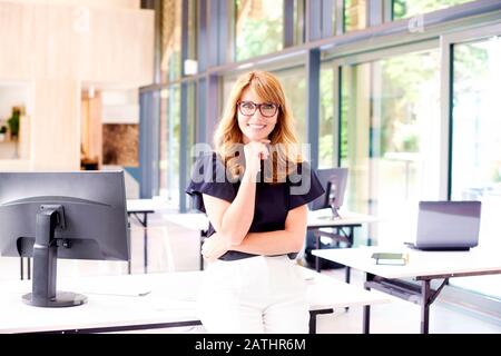 Aufnahme einer Geschäftsfrau mittleren Alters mit einem zottigen Lächeln im Büro und Blick auf die Kamera. Stockfoto