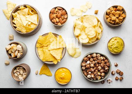 Veraity Schüsseln mit Biersnacks und Soßen auf Steintisch. Nüsse, Chips, Nachos, Cracker. Draufsicht mit Copyspace Stockfoto