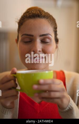 Junge Frau trinkt Kaffee zu Hause Stockfoto