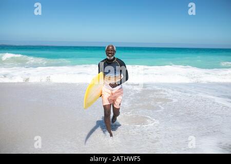 Alter Mann mit Surfbrett am Strand Stockfoto