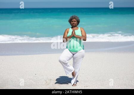 Alte Frau Yoga am Strand Stockfoto