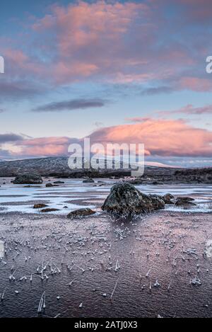 Sonnenaufgang über einer gefrorenen Lochan na h-achlaise auf Rannoch Moor nahe der Einfahrt nach Glencoe in den schottischen Highlands Stockfoto