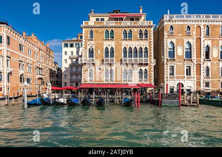 Gondeln vor dem Hotel Bauer Palazzo, wo Gäste Mittagessen auf der Terrasse vor dem Canal Grande, Venedig, Italien, genießen Stockfoto