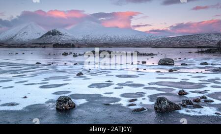 Sonnenaufgang über einer gefrorenen Lochan na h-achlaise auf Rannoch Moor nahe der Einfahrt nach Glencoe in den schottischen Highlands Stockfoto