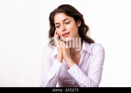 Porträtaufnahme einer schönen jungen Frau, die tagträumend sitzt, während sie auf einem isolierten weißen Hintergrund sitzt. Stockfoto