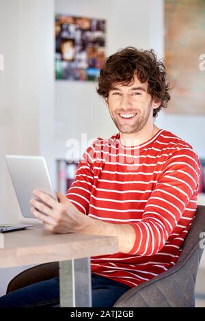 Schuss eines jungen Mannes, der am Schreibtisch sitzt und das Touchpad verwendet, während er von zu Hause aus arbeitet. Kleine Unternehmen. Stockfoto