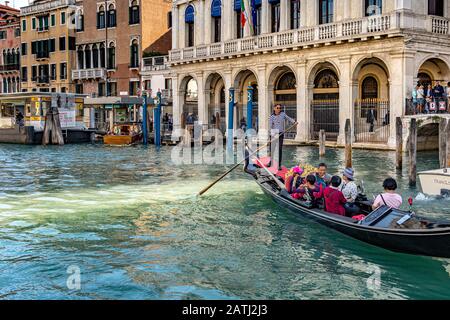 Ein Gondelier, der chinesische Touristen für eine Gondelfahrt an der Ca' d'Oro vorbeiführt, einem gotischen Palast, entlang Des Canal Grande, Venedig, Italien Stockfoto