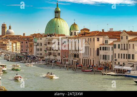 Wassertaxis auf dem Canal Grande in der Nähe des Bahnhofs Santa Lucia mit der grünen Kuppel der Piccolo-Kirche San Simeone, die die Skyline von Venedig dominiert Stockfoto