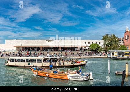 Ein Vaporetto und ein Boot, die Vorräte vor dem Bahnhof Santa Lucia, dem Hauptbahnhof in Venedig am Ufer Des Canal Grande, befördern Stockfoto