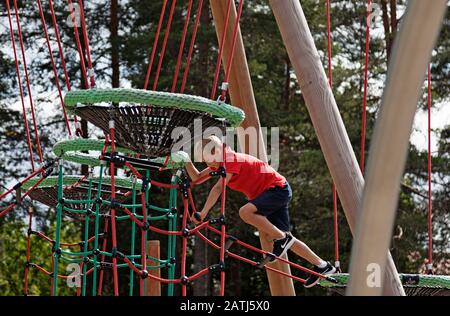 Umea, Norrland Schweden - 19. Juni 2019: Ein Junge steigt auf dem Spielplatz in ein Spielregal Stockfoto