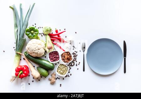 Draufsicht über frische Gemüsegruppe auf weißem Hintergrund mit Teller und Besteck . Kopierbereich Stockfoto