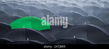 Anders und aus der Menge herausstehend gelber Regenschirm. Konzept des Führers mit vielen schwarzen Regenschirmen. Stockfoto