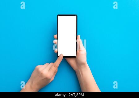 Halten Sie das schwarze Telefon auf blauem Hintergrund und im Beschneidungspfad isoliert. Smartphone-Mock-up-Konzept. Stockfoto