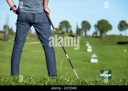 Golfflayer mit Kappe, der auf einen Golfclub mit Blick auf den Golfplatz gelehnt ist Stockfoto